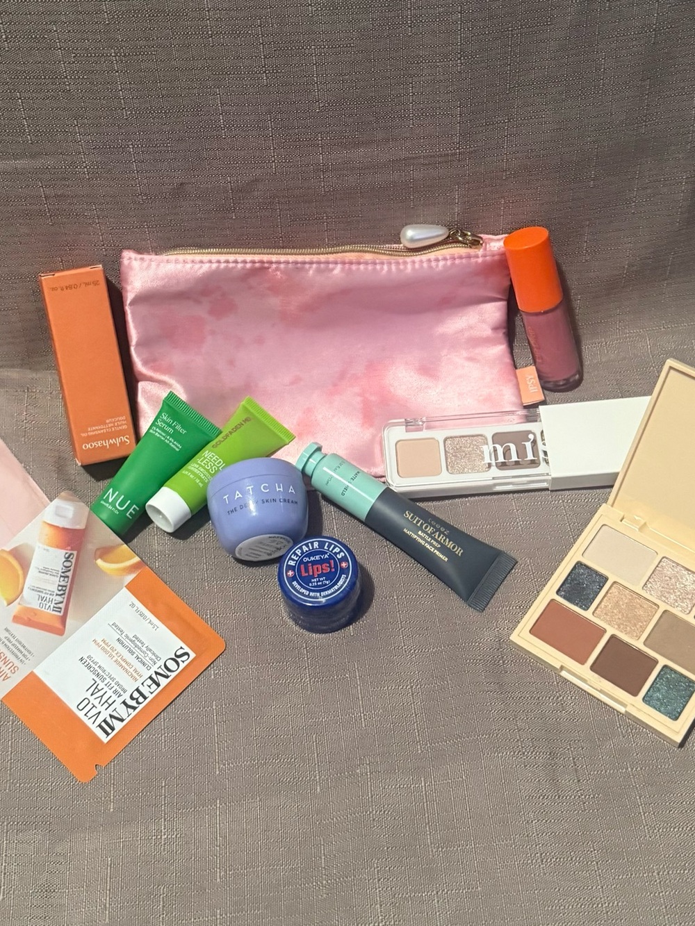 ipsy Pink Satin Makeup Pouch with assorted skin and makeup products
